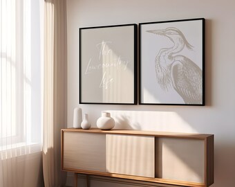 May include: Two framed prints on a white wall above a light brown wooden cabinet. The print on the left has the text "The Lowcountry Life" in white script. The print on the right is a black and white illustration of a heron.