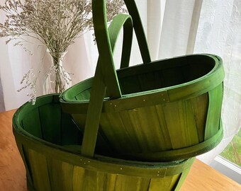 Par de cestas apilables vintage de madera partida, de color verde, ideales para recoger objetos en una casa de campo.