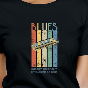 May include: A black t-shirt with a vintage-style graphic of a harmonica and the text "BLUES HARD TIMES AND TROUBLES NEVER SOUNDED SO GOOD".