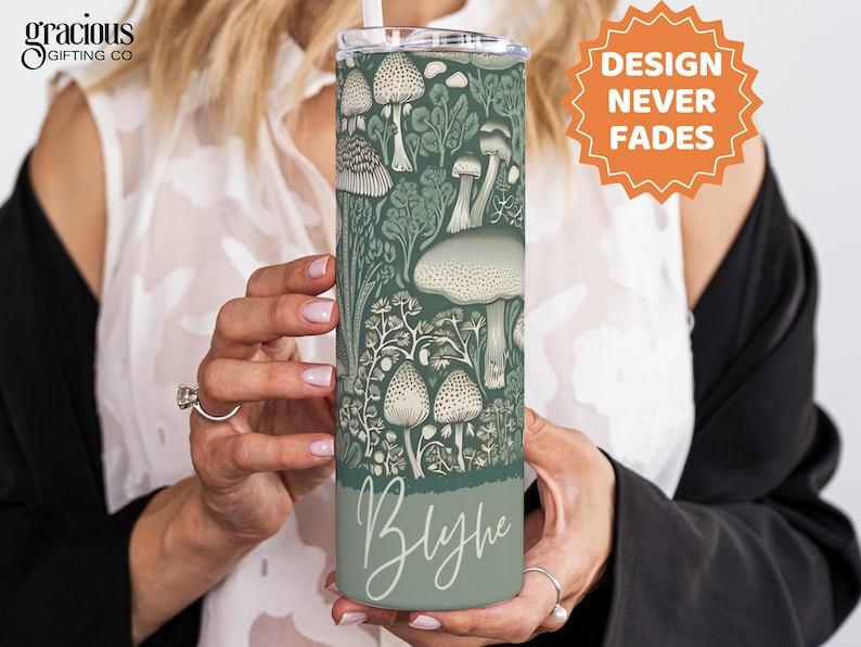 Puede incluir: Un vaso aislado verde y blanco con un dise&ntilde;o detallado de hongos y follaje. El vaso tiene una pajita y el nombre "Blythe" en una fuente de escritura. Tambi&eacute;n se ve el texto "DESIGN NEVER FADES".