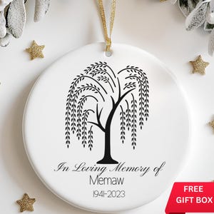 May include: White ceramic ornament with a black silhouette of a weeping willow tree. The text "In Loving Memory of Memaw 1941-2023" is printed below the tree.