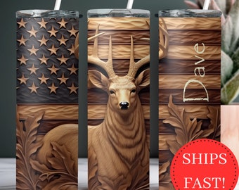 May include: Three stainless steel tumblers with different designs. The first tumbler features an American flag design. The second tumbler features a carved wooden deer head. The third tumbler features a carved wooden deer head with the name "Dave" on the side.