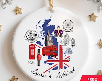 Puede incluir: Un adorno de cerámica blanca con un mapa del Reino Unido con monumentos emblemáticos como el Big Ben, un autobús de dos pisos rojo, una cabina telefónica roja y el London Eye. El adorno también incluye la bandera de la Union Jack, una corona y el texto "Laurie & Michael" y "2024".