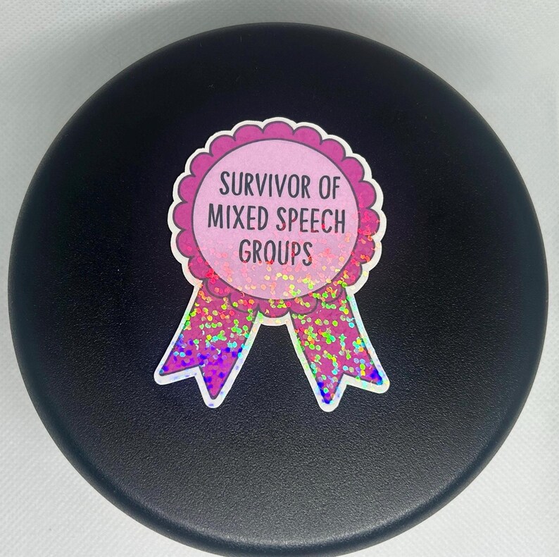 K&ouml;nnte beinhalten: Runder Aufkleber mit dem Text "Survivor of Mixed Speech Groups" in einem rosa-wei&szlig;en, gewellten Design. Der Aufkleber hat ein rosa-violettes Band mit Glitzerakzenten auf schwarzem Hintergrund.