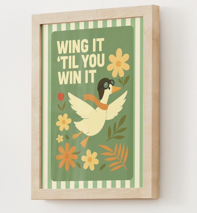 May include: A framed art print featuring a cartoon duck wearing a pilot's cap and scarf, with the text "WING IT 'TIL YOU WIN IT" on a green background. The artwork includes flowers and leaves in shades of yellow, orange, and green.