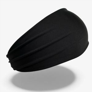 Puede incluir: Una diadema negra hecha de un material suave y elástico. La diadema ancha está diseñada para adaptarse cómodamente alrededor de la cabeza. Es de color negro sólido y parece ser sin costuras.