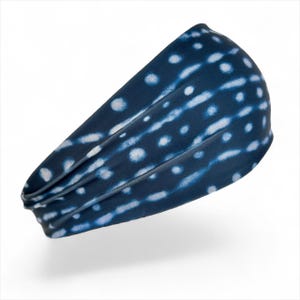 May include: A navy blue headband with a white dotted pattern. The headband is made of a soft, stretchy material and is designed to fit comfortably around the head. The pattern is a mix of dots and lines.