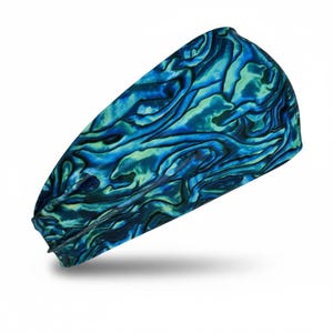 Puede incluir: Una diadema de tela ancha con un patrón abstracto vibrante y arremolinado en tonos azul océano profundo, turquesa y verde lima, que recuerda a las texturas iridiscentes de la concha de abulón con un diseño de superficie liso y continuo.
