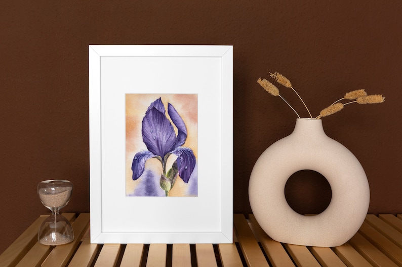 May include: A framed watercolor painting of a purple iris flower with water droplets on the petals. The painting is set against a yellow and orange background.