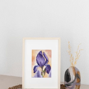 May include: A framed watercolor painting of a purple iris flower with water droplets on the petals. The painting is set against a light orange background.