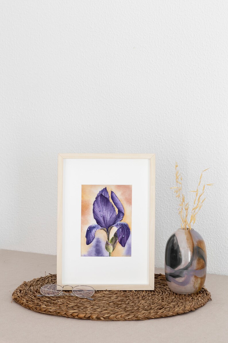 May include: A framed watercolor painting of a purple iris flower with water droplets on the petals. The painting is set against a light orange background.