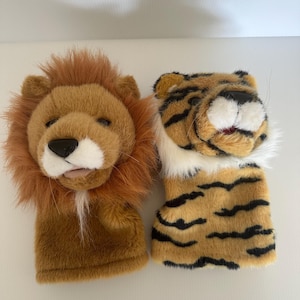 May include: Two plush hand puppets, one a brown lion with a fluffy mane and the other a brown and black striped tiger.
