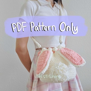 May include: A white crocheted bucket bag with pink bunny ears. The bag has a drawstring closure and a long strap. The text "PDF Pattern Only" is written in purple on a white background.
