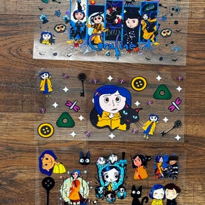 May include: Three clear sheets featuring Coraline character illustrations, including Coraline in a yellow raincoat, a black cat, keys, buttons, and various small icons. The text Coraline is printed in a stylized blue font on the top sheet.