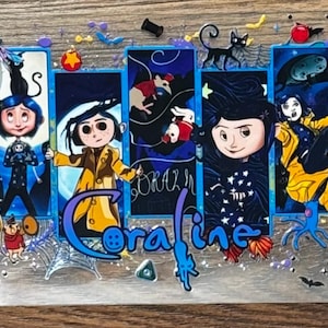 May include: A rectangular clear acrylic sheet featuring a multi-panel illustration of the character Coraline. The design includes the blue-haired protagonist in various outfits, a black cat, keys, buttons, and spiderwebs, with the text Coraline.