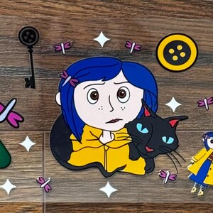 May include: A clear sticker sheet featuring a central illustration of a blue-haired character in a yellow raincoat holding a black cat, surrounded by smaller motifs including yellow buttons, green triangles, black skeleton keys, and pink dragonflies.