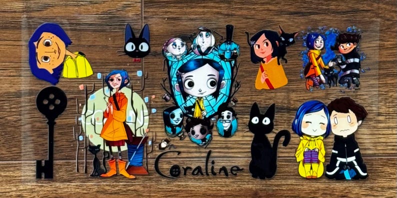 May include: A clear sheet of Coraline-themed stickers featuring various illustrations of the character with blue hair, a yellow raincoat, a black cat, a skeleton key, and other figures. The word Coraline is printed in black script at the bottom.