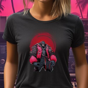 May include: A black t-shirt with a graphic of a gorilla wearing a red jacket and standing in front of a red sun. The gorilla is wearing a black belt and has a red bandana around its neck.