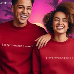 May include: Two people wearing red sweatshirts with the text "[ long romantic pause ]" printed on them. The sweatshirts are a crew neck style.