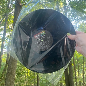 May include: A black vinyl record in a clear plastic sleeve. The record label is visible and reads "Dunhill" and "Golden Biscuits" "Three Dog Night".