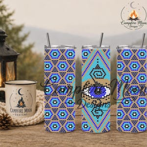 May include: Three cylindrical tumblers with metal straws featuring a repeating geometric pattern in shades of blue, black, and tan. The design includes a central eye motif on the middle tumbler. The tumblers have a smooth, glossy finish.