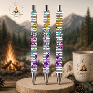 Op de afbeelding: Drie intrekbare pennen met een witte achtergrond en een herhalend patroon van kleine, kleurrijke geometrische vormen in geel, roze, paars en blauw. Elke pen heeft een zilverkleurige metalen punt en een zilverkleurig klikmechanisme.