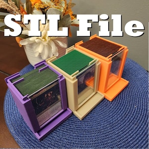 Può includere: Tre scatole per la conservazione delle carte stampate in 3D. Le scatole sono viola, beige e arancioni. Le scatole sono etichettate "Jatana and Alena, Partners - 2020".