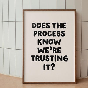 Peut inclure: Une impression encadrée avec le texte "Does the process know we're trusting it?" en lettres noires en gras sur un fond blanc. Le cadre est en bois brun.