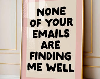 May include: A framed art print with a gold frame and a pink border. The print features the text "NONE OF YOUR EMAILS ARE FINDING ME WELL" in bold black letters on a beige background.