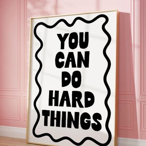 Puede incluir: Un póster motivacional en blanco y negro con un borde ondulado. El texto en el póster dice "You can do hard things."