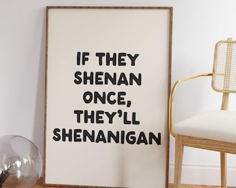 May include: A framed print with the text "IF THEY SHENAN ONCE, THEY'LL SHENANIGAN" in bold black letters. The print is in a wooden frame and is leaning against a white wall. A chair with a gold frame and a glass vase are also in the image.