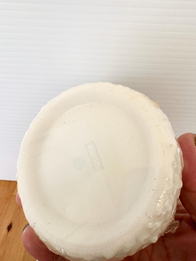 Puede incluir: Una pila de platos blancos, redondos y desechables, envueltos en pl&aacute;stico transparente. Los platos tienen un borde ligeramente texturizado y la palabra "AVON" es visible en la parte inferior.