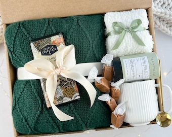 Elegante confezione regalo: coperta, tazza, calzini e prelibatezze gourmet.