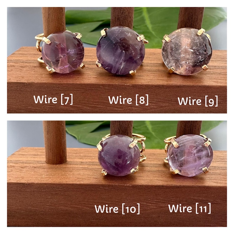 May include: Five gold rings with purple amethyst stones. The rings are displayed on a wooden stand. Wire [7], Wire [8], Wire [9], Wire [10], Wire [11].