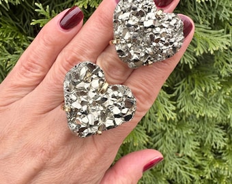 May include: Two gold rings with heart-shaped pyrite stones. The stones are a rough, natural, and sparkly silver color.