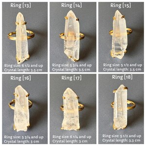 May include: Six gold rings, each with a clear quartz crystal. The rings are set against a grey background. Text on the image indicates ring sizes and crystal lengths, with the longest crystal measuring 3.5 cm.