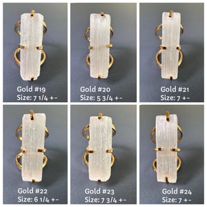 May include: Six gold-toned rings featuring rectangular white selenite stones held by four prongs. Each ring is labelled with a number and a US size: Gold #19 size 7 1/4, #20 size 5 3/4, #21 size 7, #22 size 6 1/4, #23 size 7 3/4, and #24 size 7.