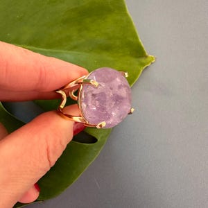 May include: A gold ring with a large, round, light purple amethyst gemstone.