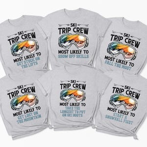 May include: Six light gray t-shirts with the text "SKI TRIP CREW" and a graphic of ski goggles. Each shirt has a different phrase: "Most Likely to Get Stuck on the Lifts", "Most Likely to Show Off Skills", "Most Likely to Fall the Most", "Most Likely to Get Lost on the Mountain", "Most Likely to Take the Longest to Put on Ski Boots", and "Most Likely to Start a Snowball Fight".