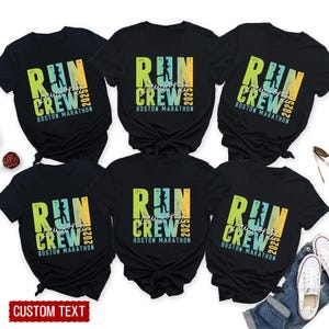 Op de afbeelding: Zes zwarte t-shirts met de tekst "RUN CREW BOSTON MARATHON 2025" in een verloop van groen, geel en blauw. De shirts hebben een silhouet van een hardloper. De tekst "CUSTOM TEXT" staat onderaan.