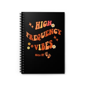 May include: A black spiral-bound notebook with the words "HIGH FREQUENCY VIBES" in orange and peach lettering. The notebook features floral and star graphics, with the text "Nicu RT" and baby footprints at the bottom.
