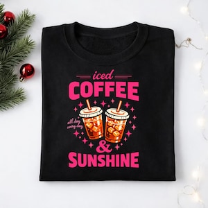 Könnte beinhalten: Schwarzes Sweatshirt mit dem Schriftzug "iced COFFEE & SUNSHINE" in Pink, zusammen mit Illustrationen von Eiskaffees. Der Satz "all day every day" ist ebenfalls enthalten. Das Design ist von rosa Sternen umgeben.