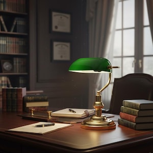 May include: A traditional green banker's lamp with a brass base is on a dark wood desk. The desk has books, a pen, and a notepad. A leather chair and a bookcase filled with books are in the background.