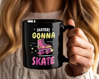 May include: Black ceramic mug with the text "SKATERS GONNA SKATE" in yellow and pink. A pink roller skate graphic is featured in the center. The mug has a black handle and is held by a person.