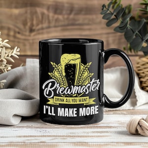 May include: Black ceramic mug with a curved handle. The mug features the word "Brewmaster" in a stylized script, along with a beer glass graphic and the text "DRINK ALL YOU WANT I'LL MAKE MORE."