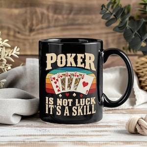 May include: A black ceramic mug featuring a graphic of a royal flush poker hand in hearts. The text reads POKER IS NOT LUCK IT'S A SKILL in a beige font, set against a retro-style horizontal striped background of blue, yellow, and red.