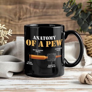 Peut inclure: Mug en céramique noire avec l'inscription dorée "ANATOMY OF A PEW". Le mug présente un schéma d'une balle avec des étiquettes telles que "Metal Holdy Thing" et "Magical Fire Dust".