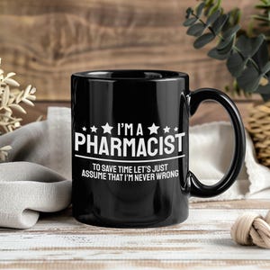 May include: A black ceramic mug featuring white printed text that reads I'M A PHARMACIST TO SAVE TIME LET'S JUST ASSUME THAT I'M NEVER WRONG, accented with small white stars above the word PHARMACIST and a horizontal line separating the two phrases.