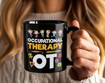 May include: Black ceramic mug with the words "OCCUPATIONAL THERAPY OT" in yellow and white. The mug features cartoon children and occupational therapy tools. The mug has a black handle and is held by a person.