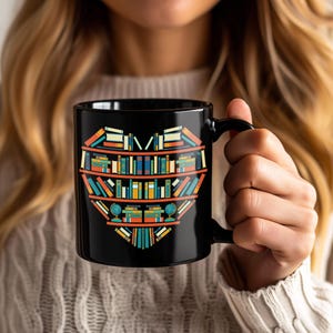 May include: Black ceramic mug featuring a heart-shaped design composed of colorful books arranged on shelves. The books are in various colors, including blue, orange, yellow, and green. The mug has a black handle and a glossy finish, perfect for book lovers.